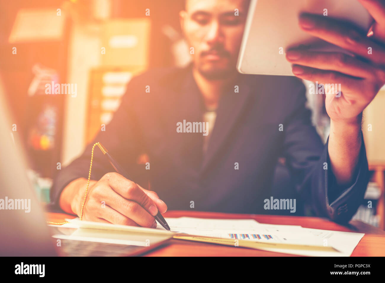 Businessmen are analyzed data from report using smartphone and laptop computer. Stock Photo