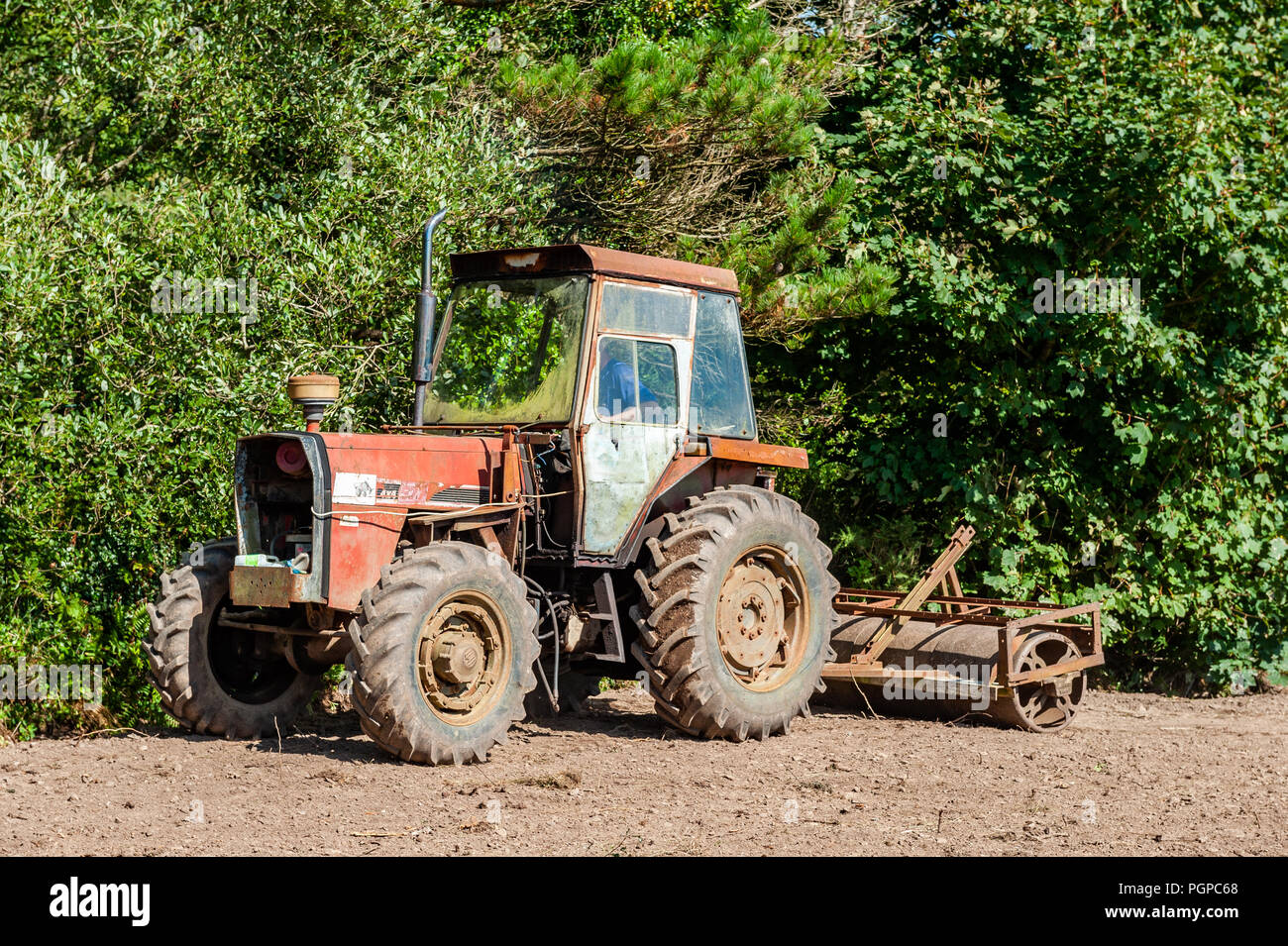 Farmer rolls ground after planting grass seed on a sunny day in Ballydehob, West Cork, Ireland with copy space. Stock Photo