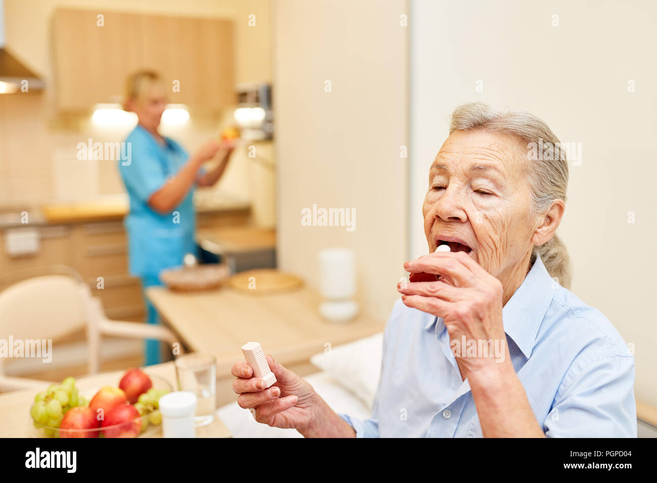 Old woman in her senior apartment creams her lips in assisted living Stock Photo
