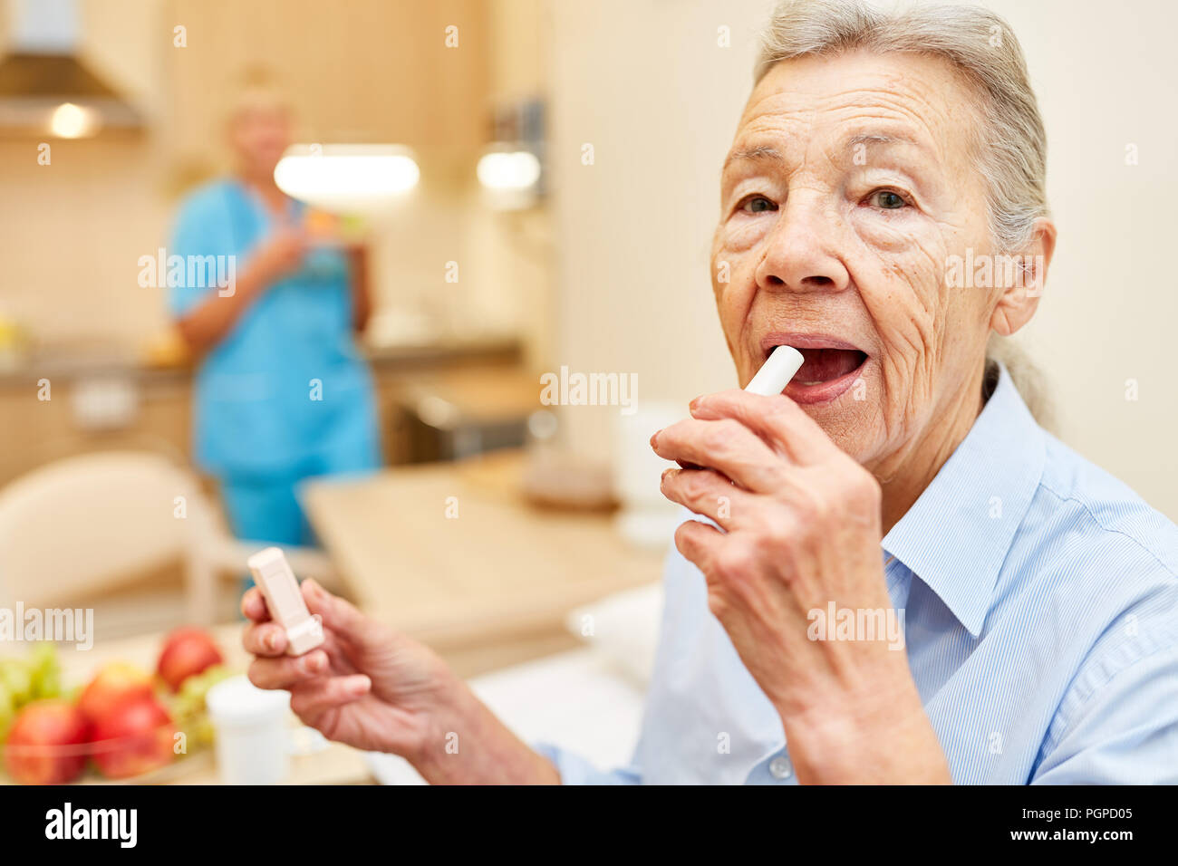 Senior woman creams her lips with lip cream in her senior citizen home Stock Photo
