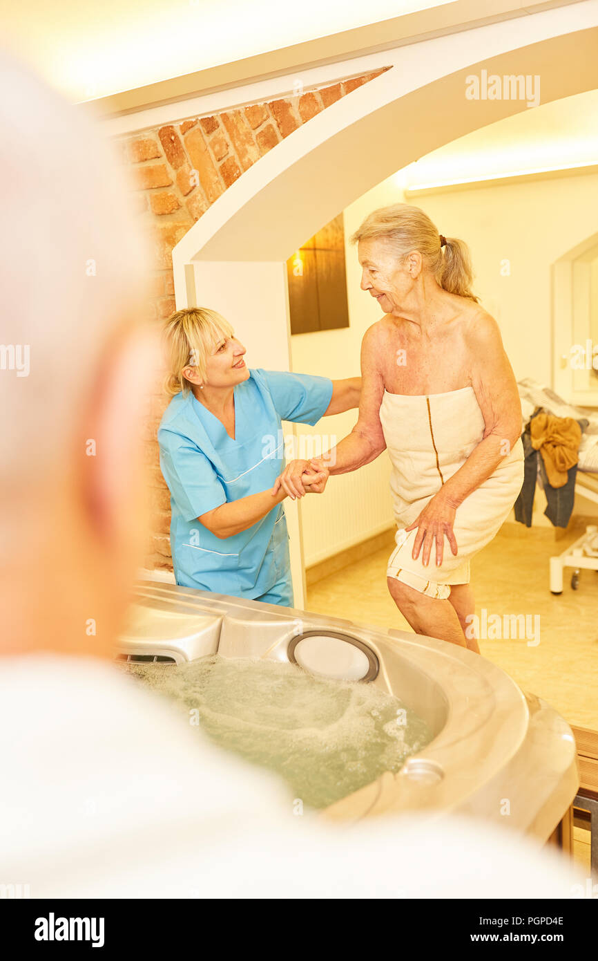 Caregiver helps senior woman while bathing in the hot tub of the senior residence Stock Photo