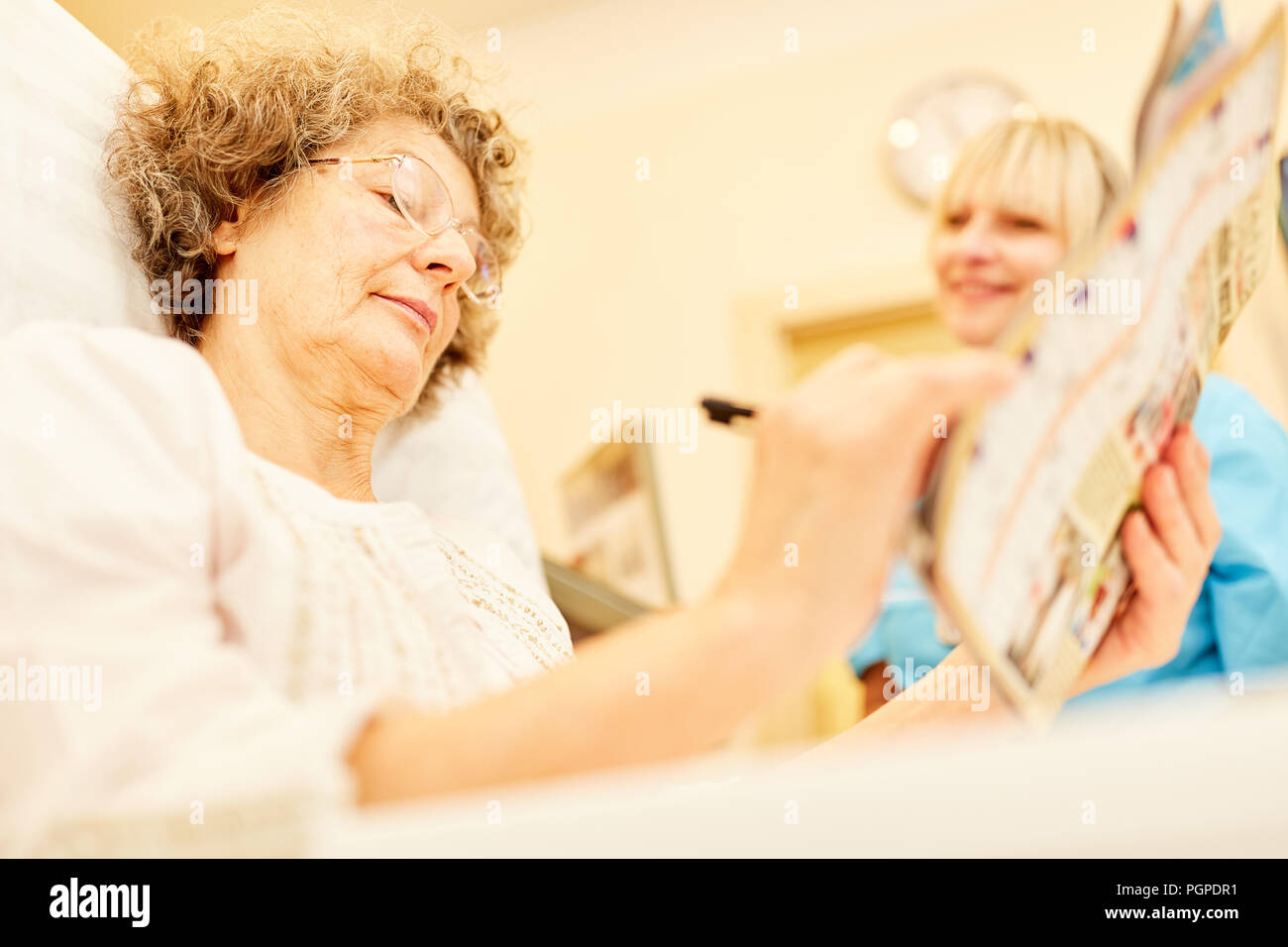 Senior woman as a patient with dementia solves crossword puzzle in