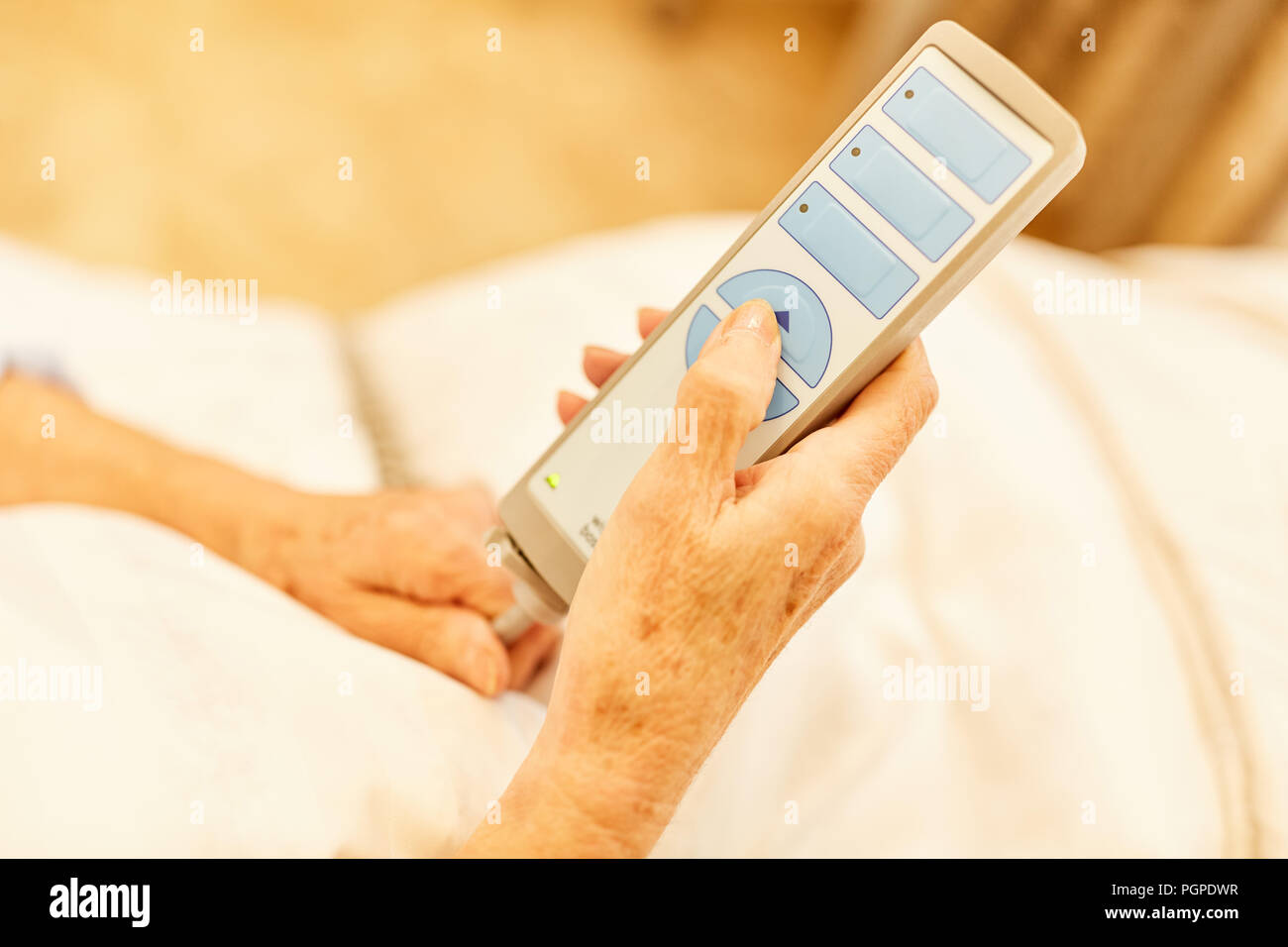 Hands of a senior citizen as a patient hold the remote control from the