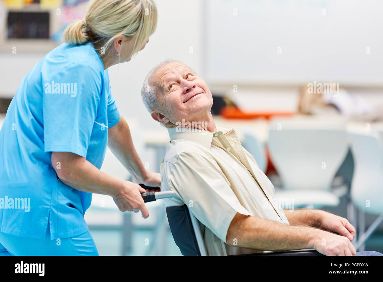 Demented senior in wheelchair is being cared for by a nurse in geriatric care Stock Photo