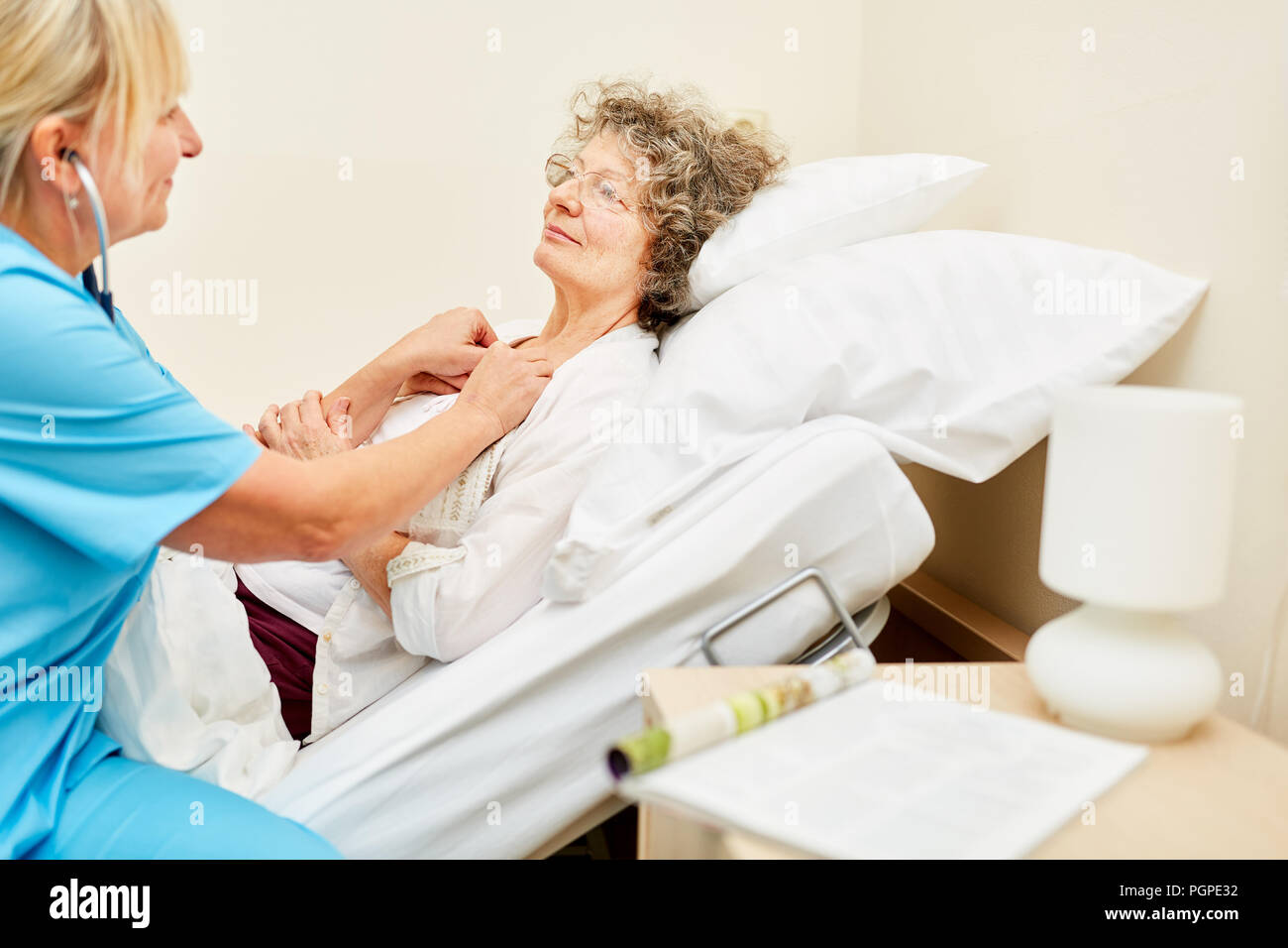 A bedridden old woman is being listened to by a doctor with a stethoscope Stock Photo