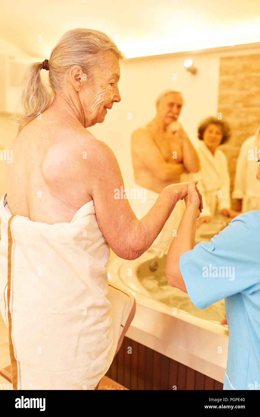 Caregiver helps senior woman in the spa spa while bathing in the hot ...