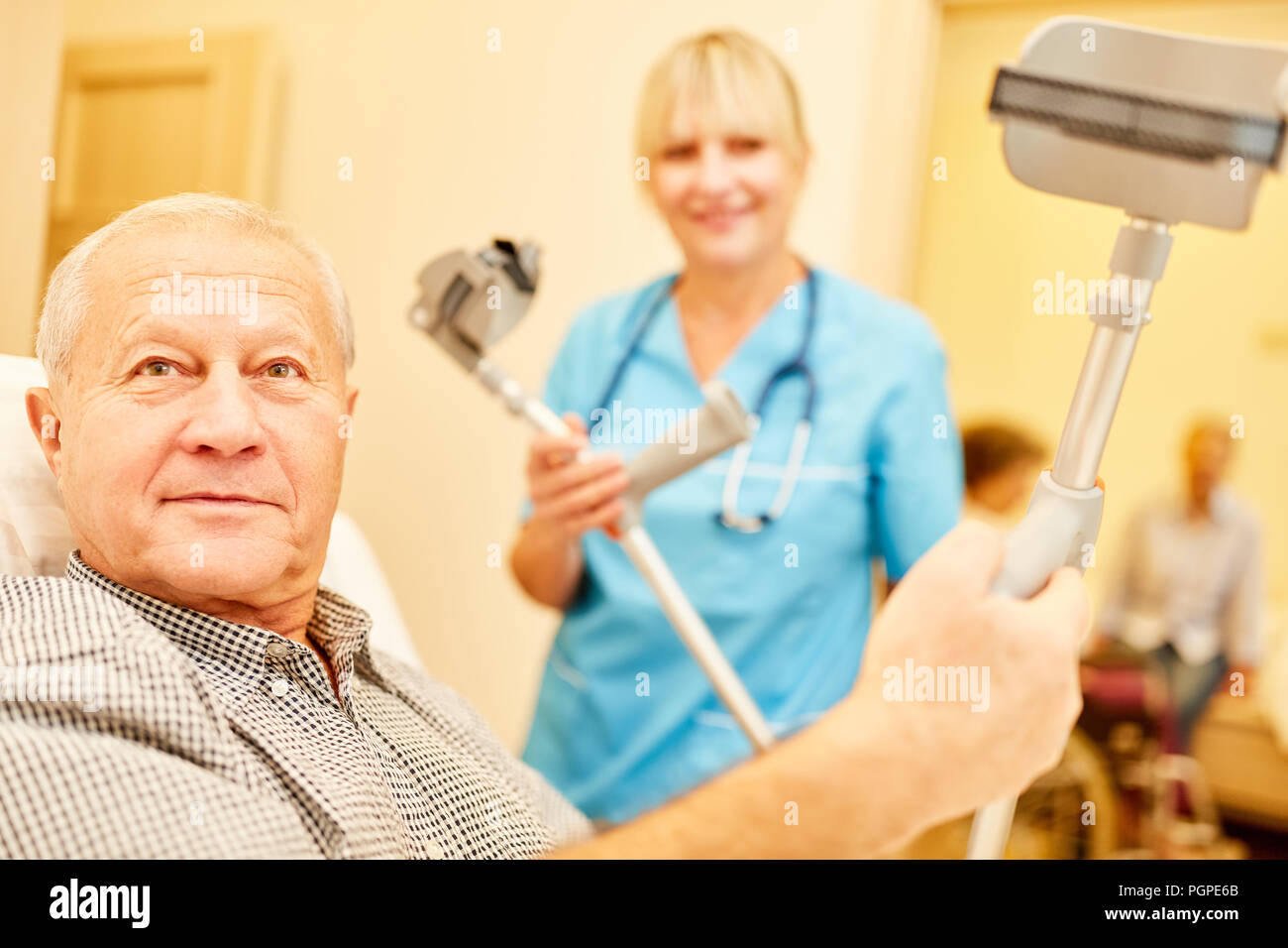 Disabled senior man in retirement home with crutches and caregiver in