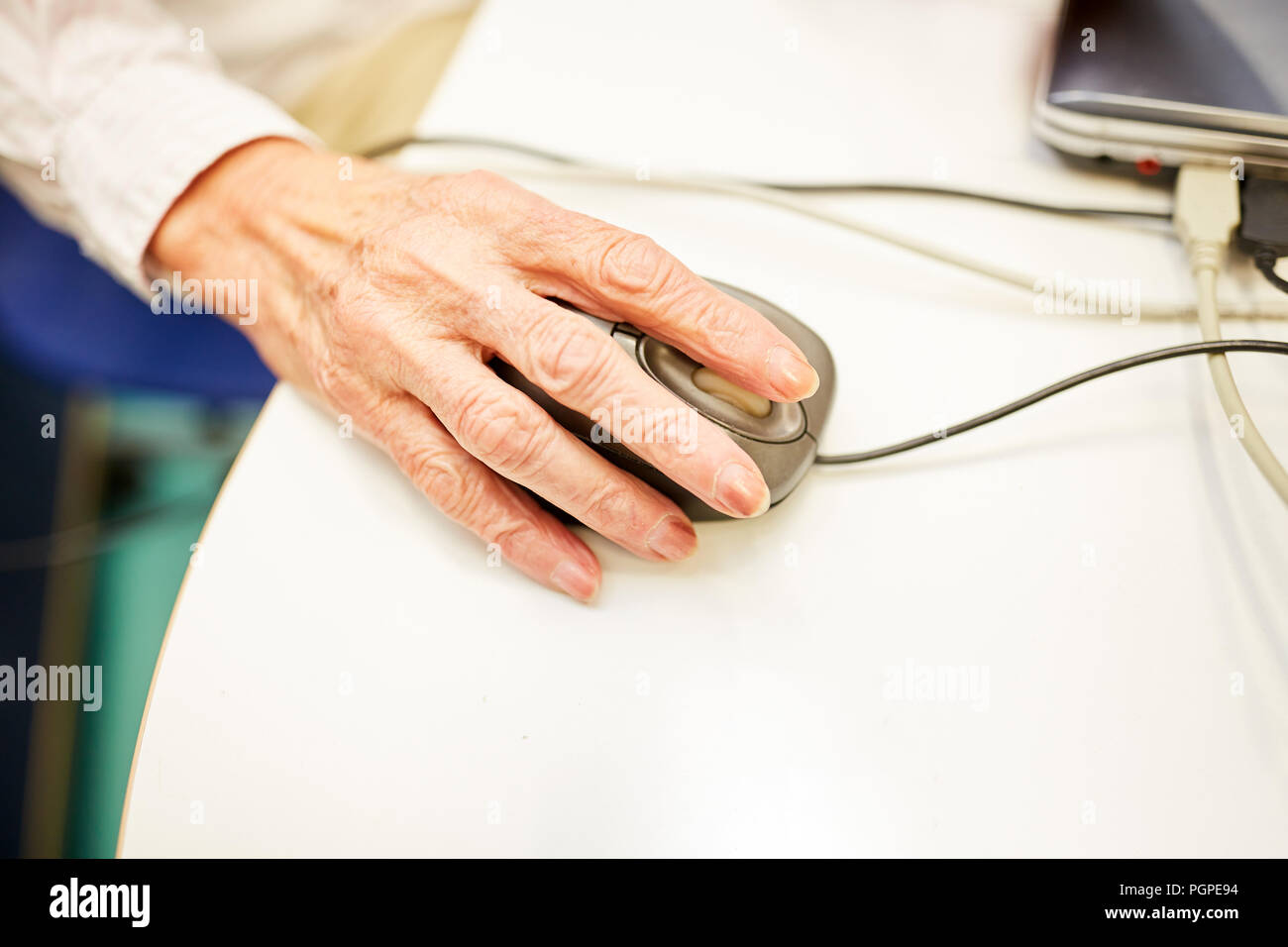 Wrinkled hand of a senior woman at the computer mouse in the PC course in the retirement home Stock Photo