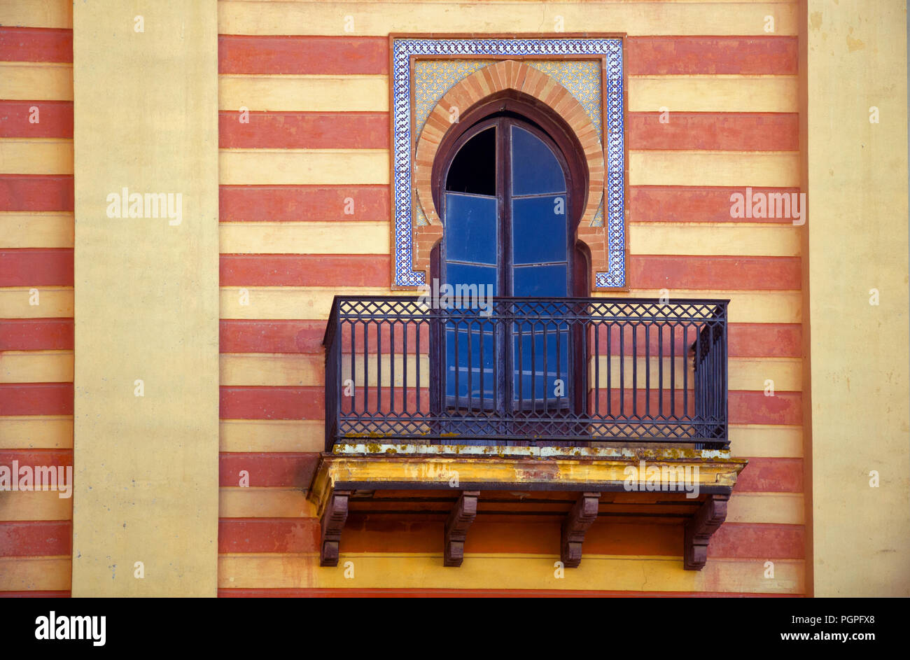 Decorative window in spanish style on the striped red yellow wall Stock