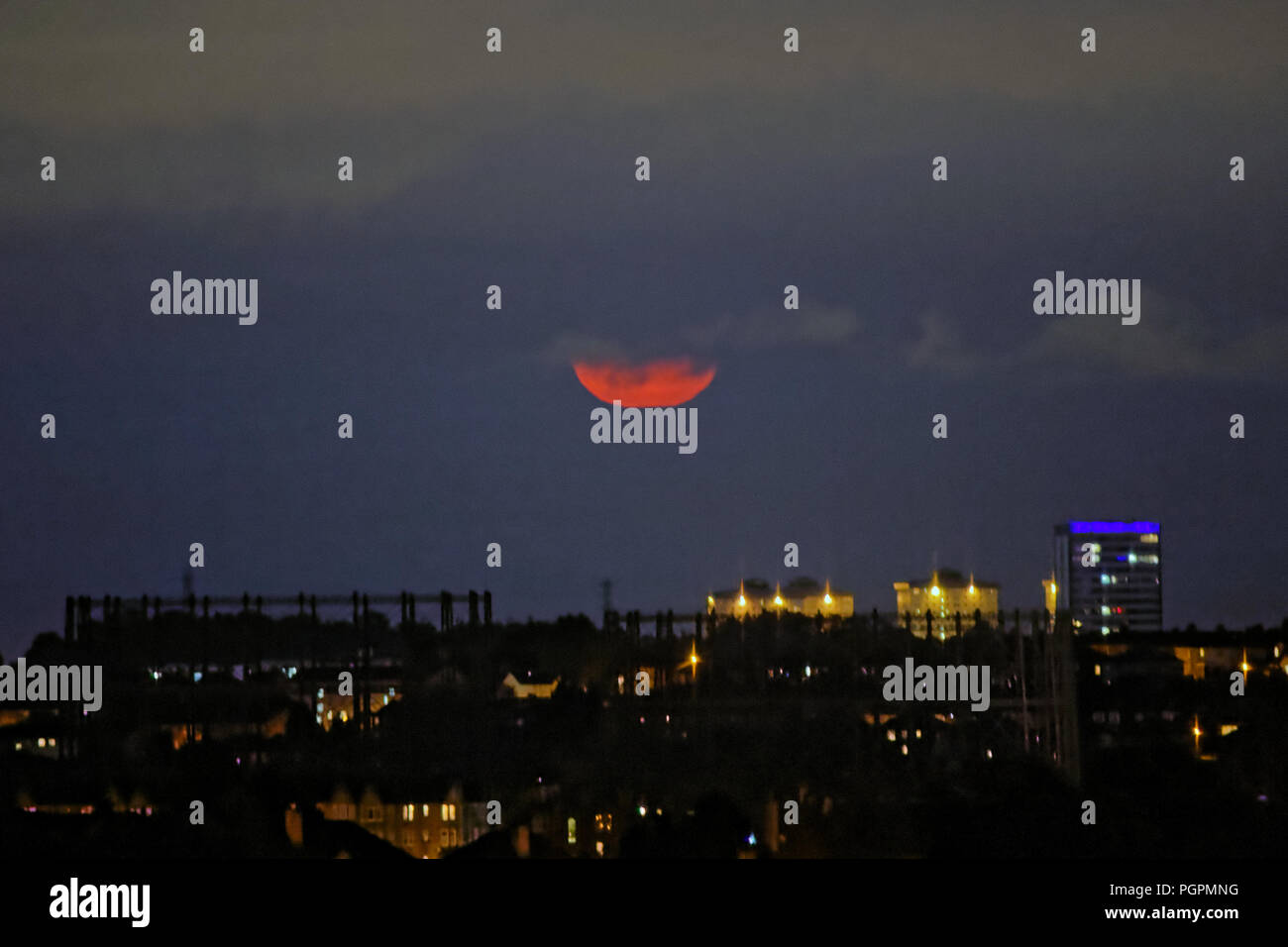 Glasgow, Scotland, UK. 27th  August, 2018. UK Weather: August's Sturgeon  bottom Moon over Glasgow goes red amongst the cloudy sky with the  kelvindale gasometers and the towers of maryhill in the  in the west end of the city. This months bottom  moon was unfortunately not named after Nicola but after North America's largest fish, the lake sturgeon. Gerard Ferry/Alamy news Credit: gerard ferry/Alamy Live News Stock Photo