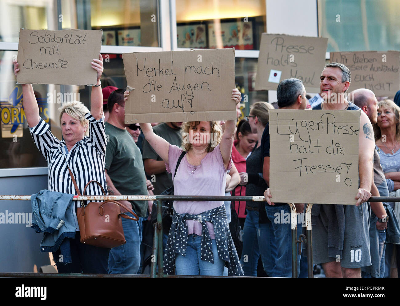 Cologne, Germany. 28th Aug, 2018. Participants in a rally of right-wing groups hold up posters. Left and right groups demonstrate after the events in Chemnitz, where a 35-year-old man was stabbed to death after an argument in the night to Sunday. The posters say: 'Solidarity with Chemnitz', 'Merkel open your eyes' and 'Keep your mouth shut'. Credit: Henning Kaiser/dpa/Alamy Live News Stock Photo