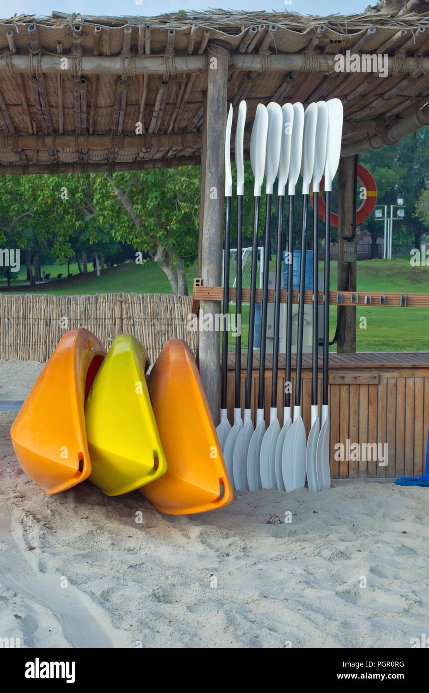 Plastic mass products kayaks of various colors are rented out on the sea sandy beach. Hot morning Dubai location shot Stock Photo