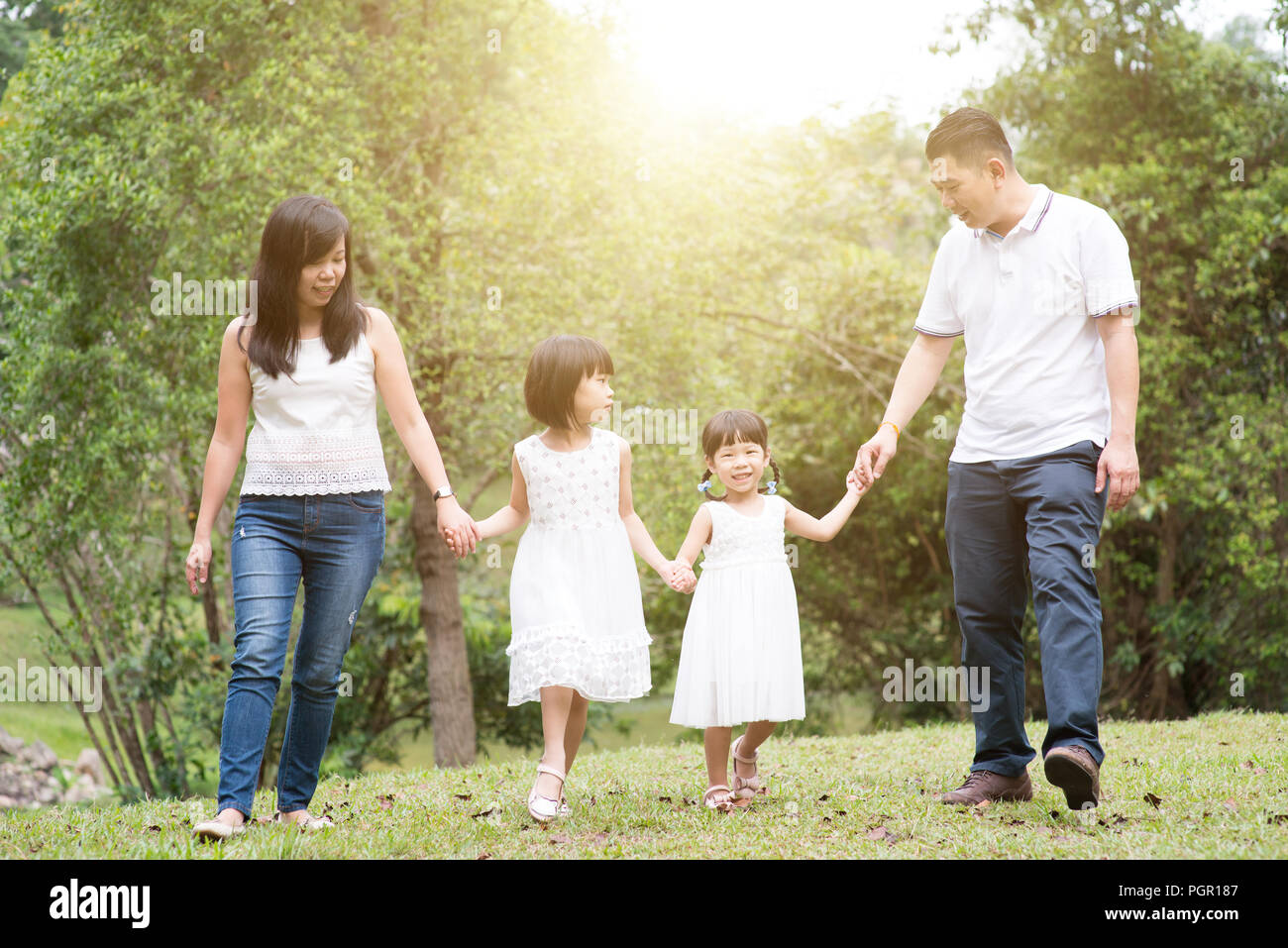 Asian Family Outdoors Parents And Children Holding Hands And Walking At Green Park Stock Photo Alamy