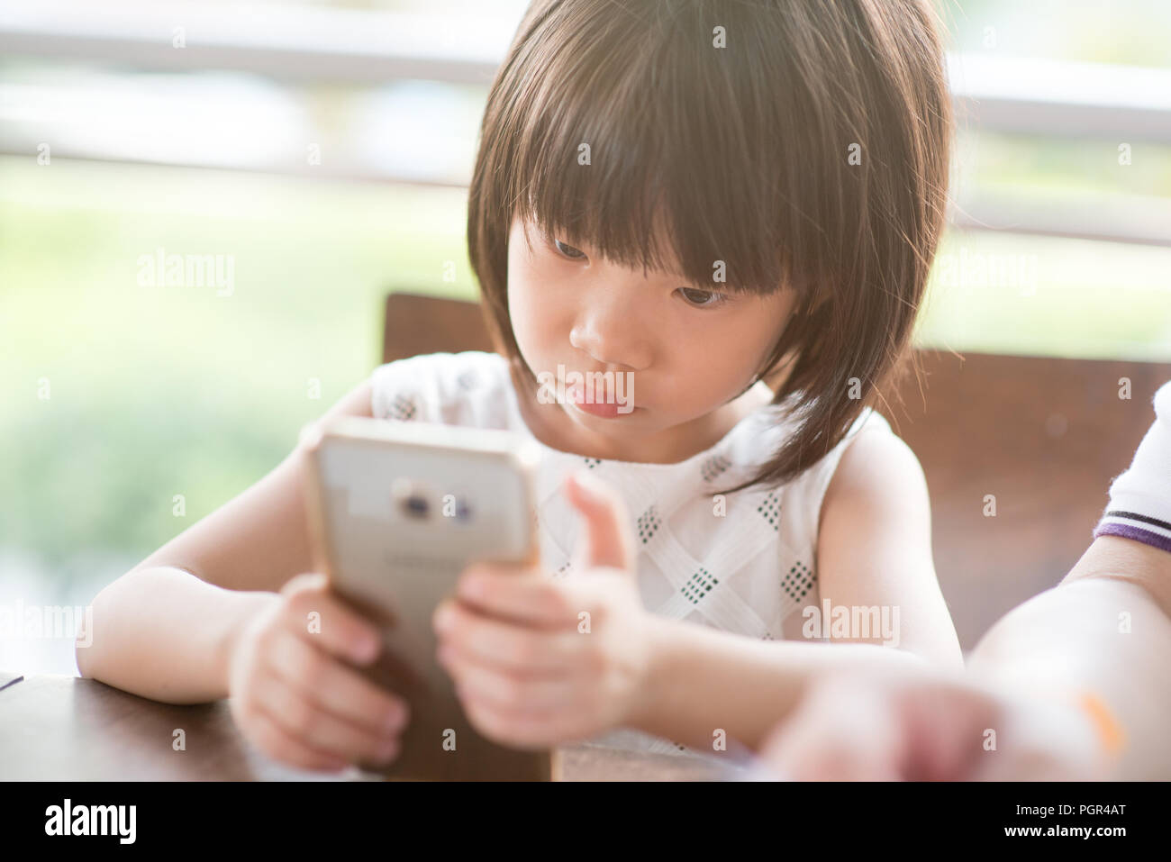 Asian Child Playing Smart Phone At Cafe Natural Light Outdoor