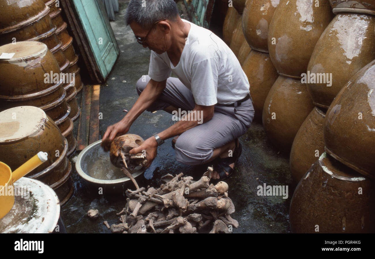 A Man removes bones from a earthenware earthenware jar and washes them ...