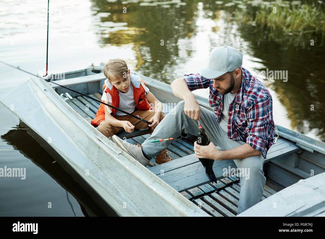 Father fishing on the boat together with his son, they are catching a ...