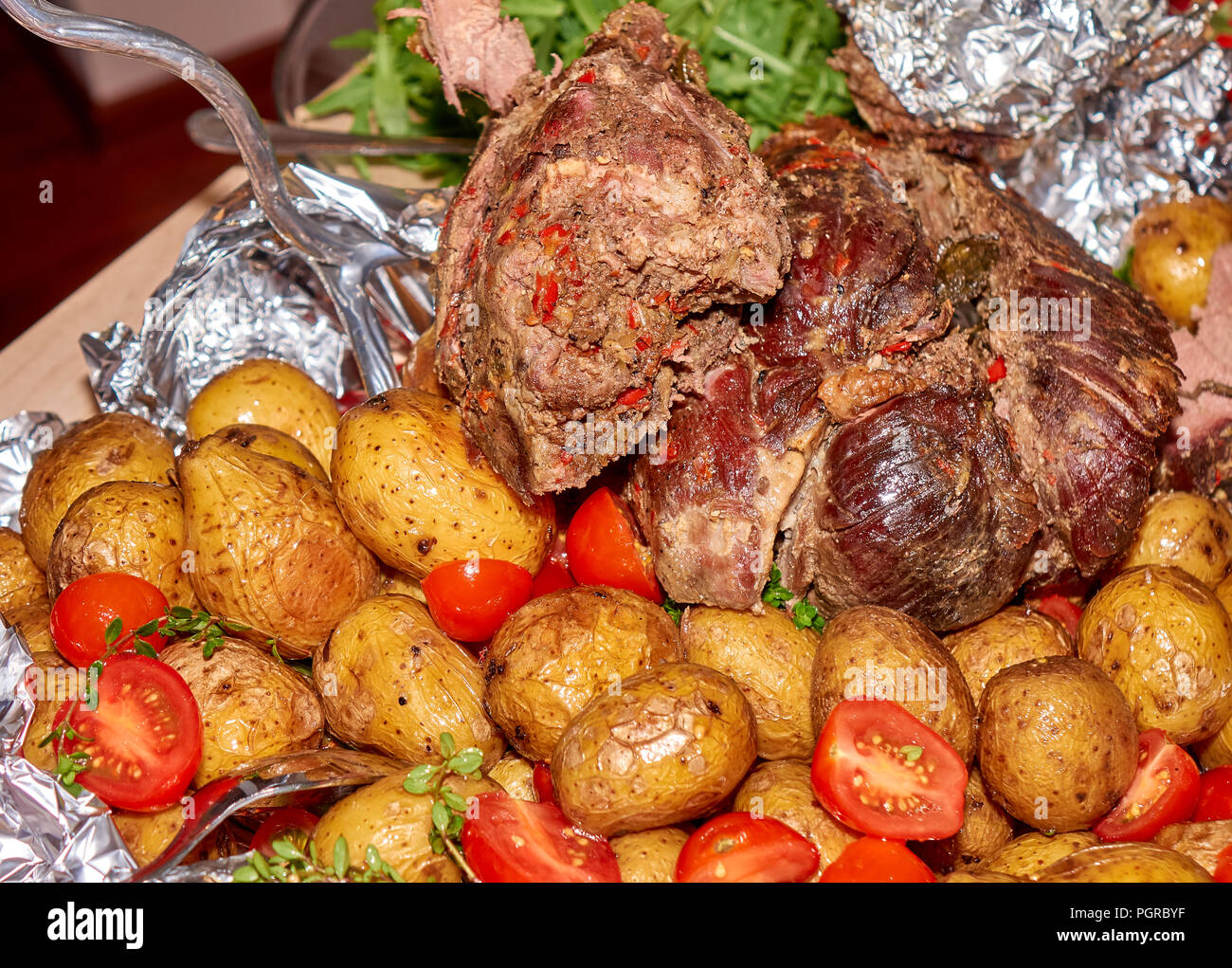 Big peace of the roasted medium well mutton meat with baked potatoes and fresh tomatoes Stock Photo