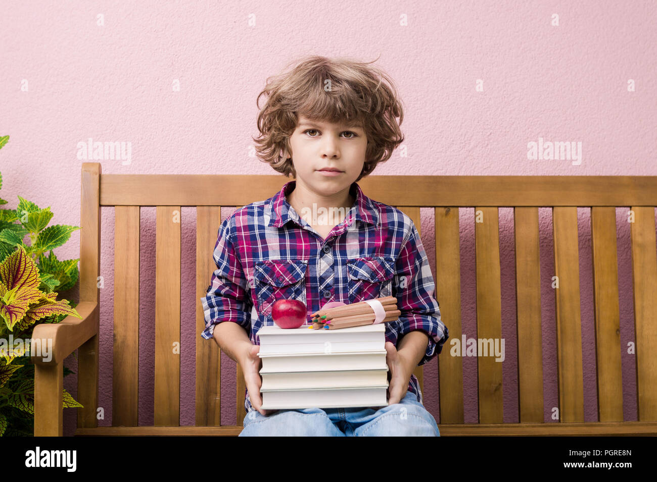 Little boy holding stack of books ready to go back to school. Stock Photo