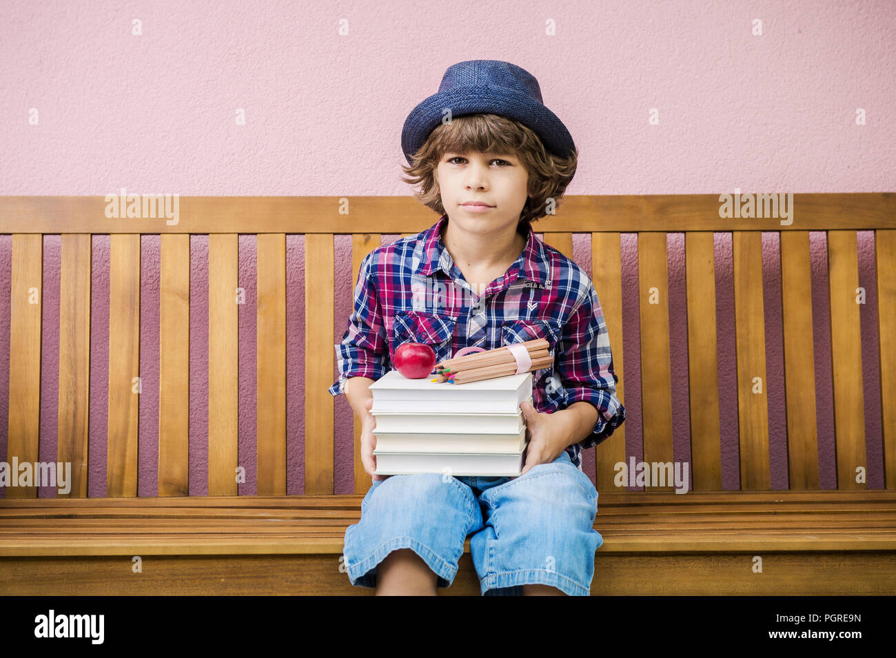 Little boy holding stack of books ready to go back to school. Stock Photo