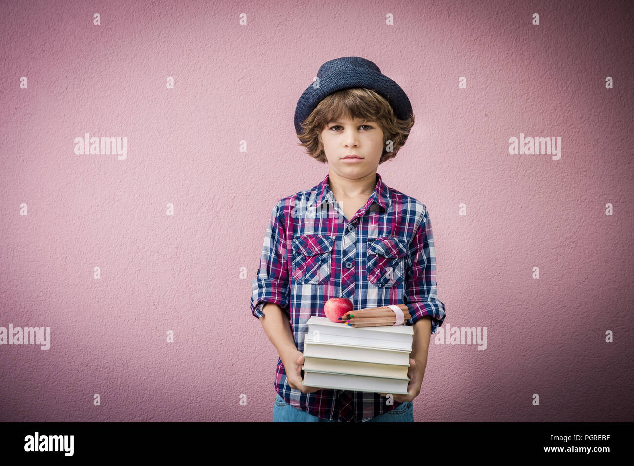 Little boy holding stack of books ready to go back to school. Stock Photo