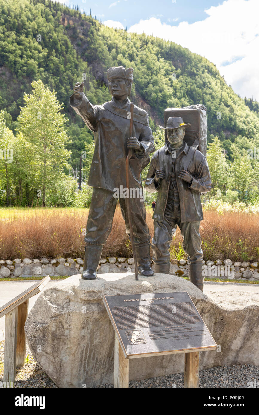 The Skagway Centennial Statue by Chuck Buchanan showing a typical prospector at the time of the Klondike Gold Rush being led by a native Tlingit guide Stock Photo