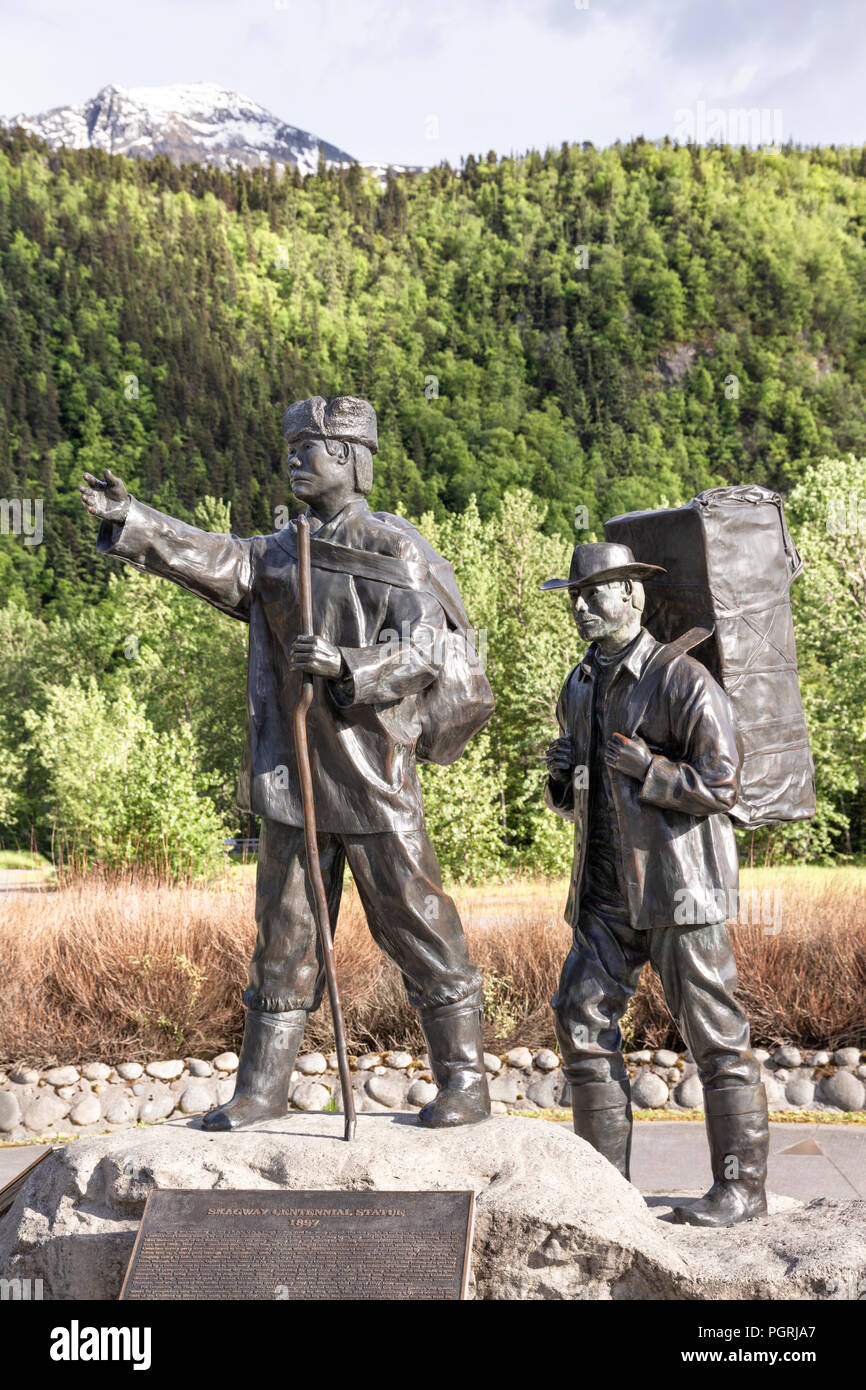 The Skagway Centennial Statue by Chuck Buchanan showing a typical prospector at the time of the Klondike Gold Rush being led by a native Tlingit guide Stock Photo