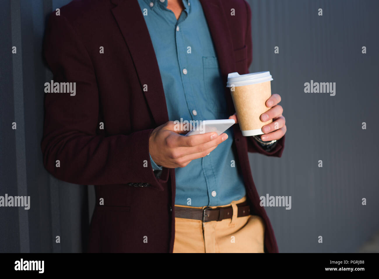cropped shot of young man holding paper cup and using smartphone Stock ...