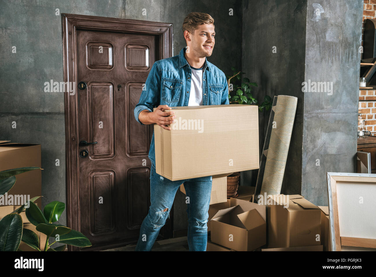 handsome young man carrying box while moving into new house Stock Photo Alamy