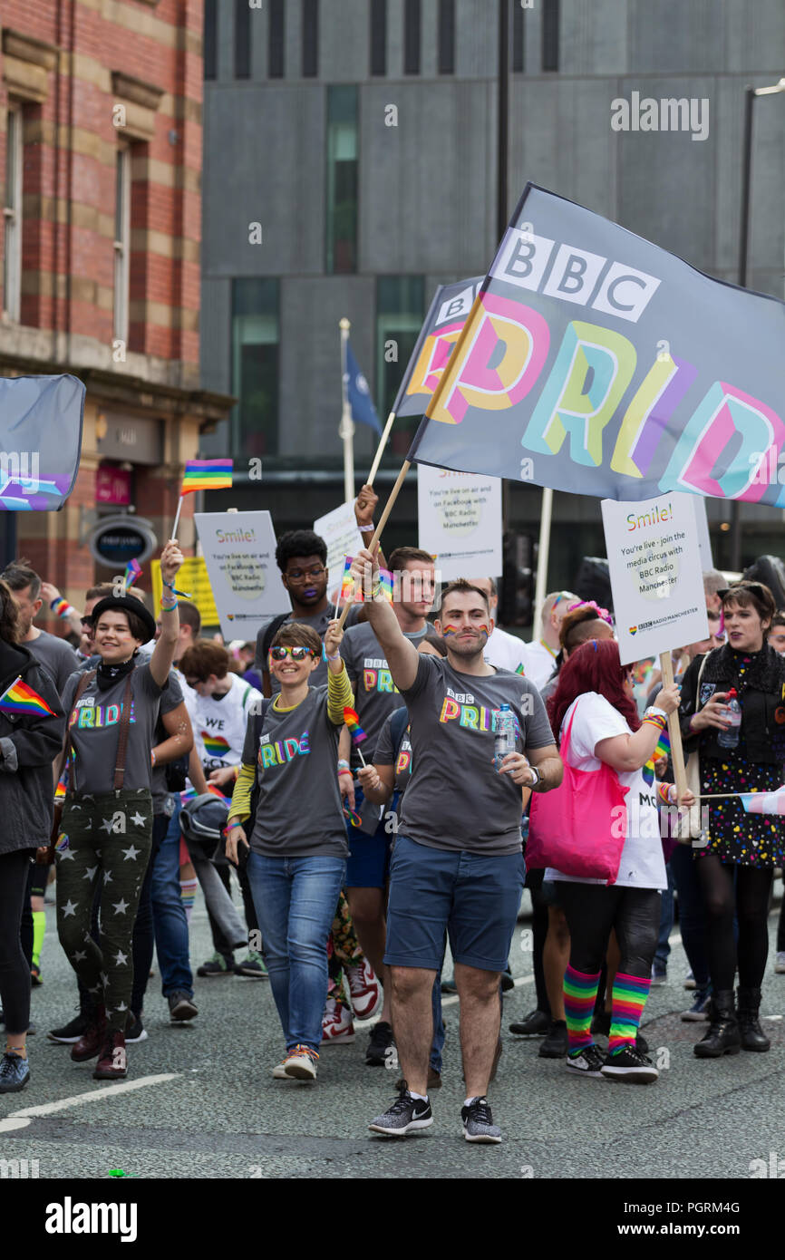 People wearing BBC Pride tee shirts carry a flag whilst taking part in the 2018 Manchester Pride Parade. Stock Photo