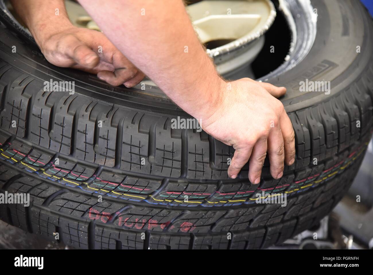 Tyre/tire fitting a new tyre being eased in to position over the wheel