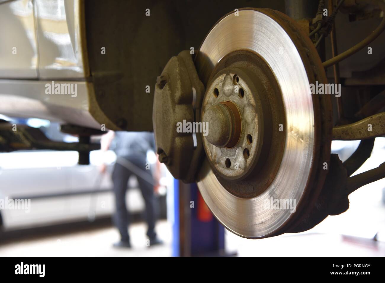 Tyre/tire fitting a vehicle raised on a ramp and a wheel removed