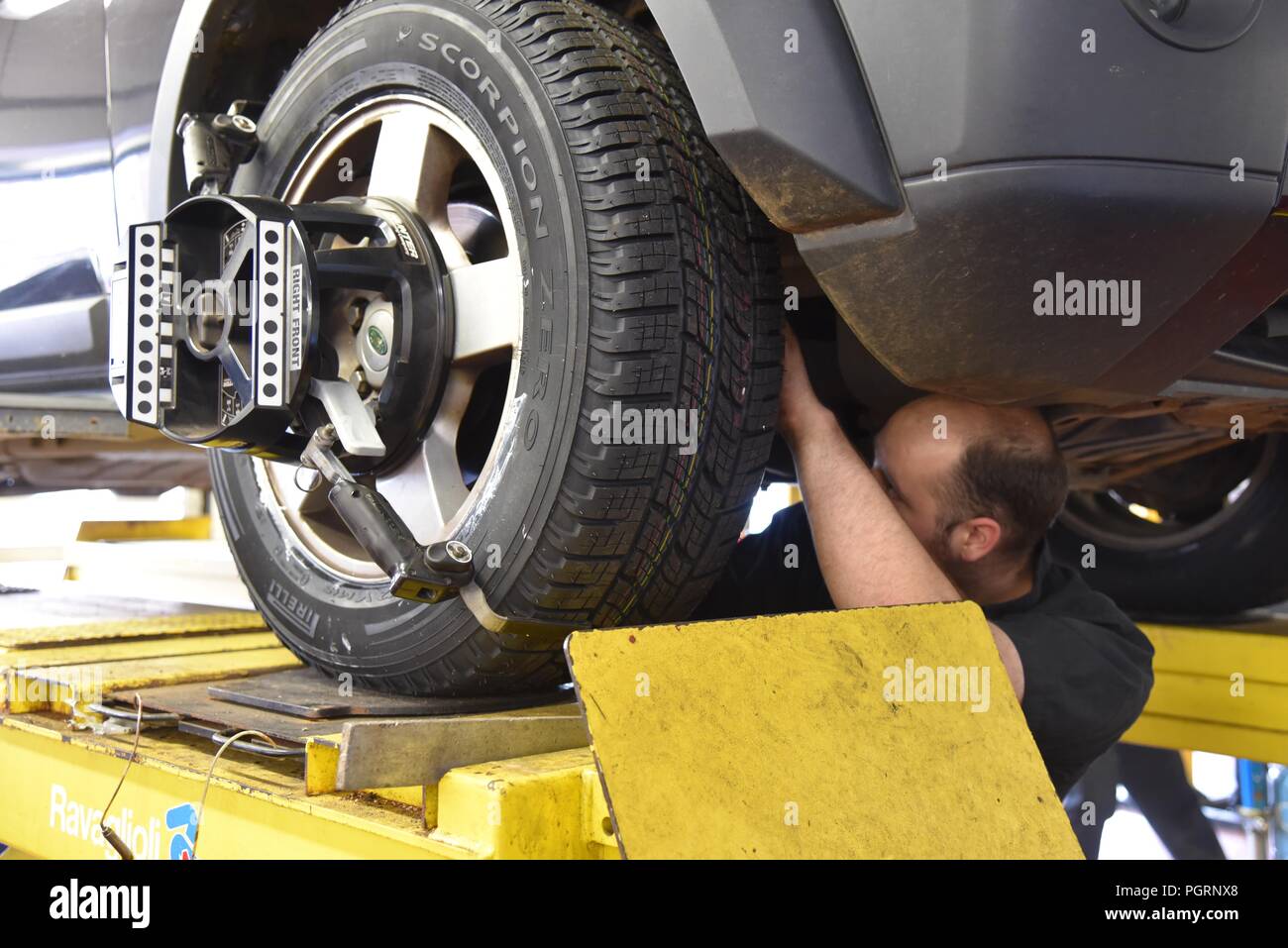 Tyre/tire fitting a mechanic on the underside of a vehicle adjusting