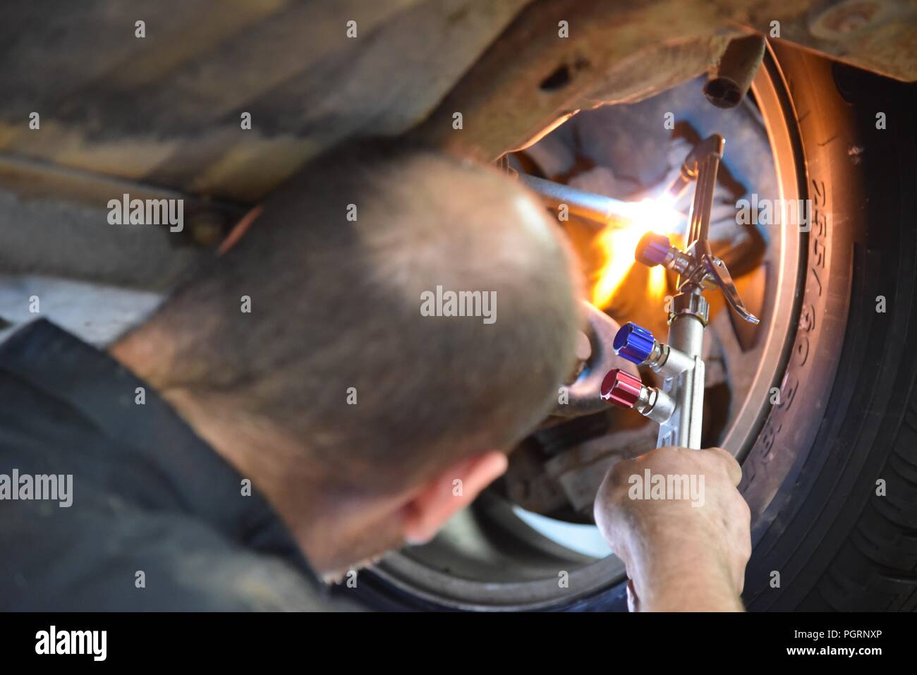 Tyre/tire fitting a mechanic using an oxyacetylene torch to aid