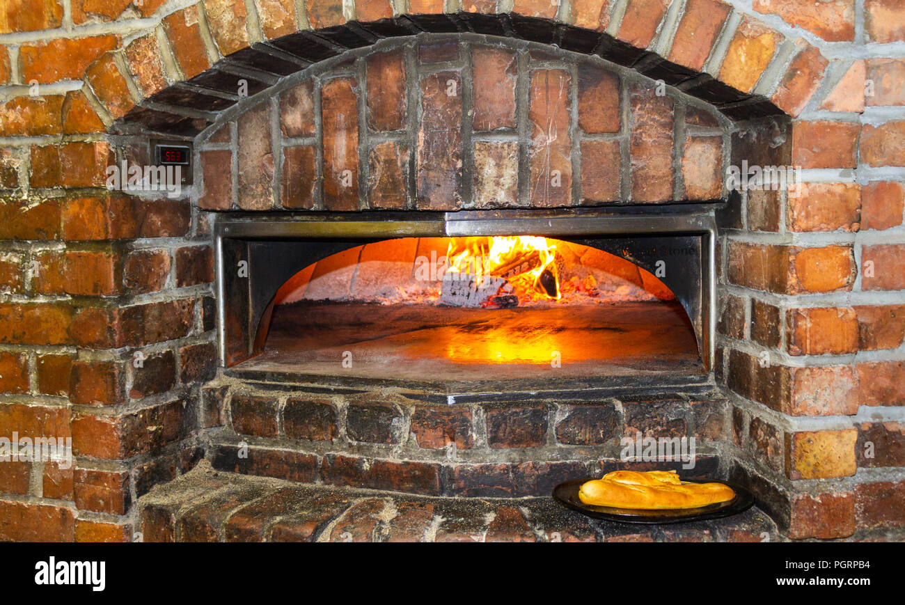 wood fired brick oven for baking bread and pizza with fire alight at the back. Stock Photo