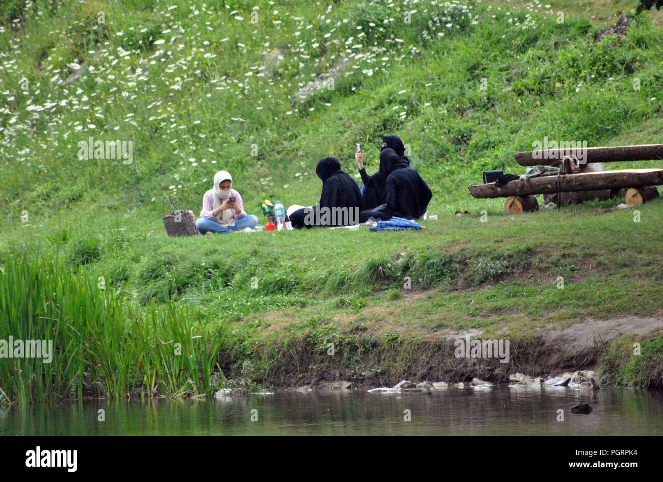 Bihac, Bosnia-Herzegovina.Picnic of muslim women using smartphone on the banks of the Una river Stock Photo