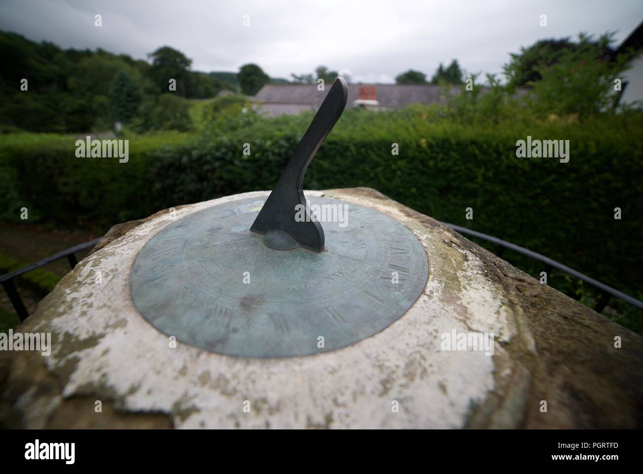 An old, vintage sun dial on top of a rock platform. A garden sundial on a pedestal. Horizontal Sundial. Stock Photo