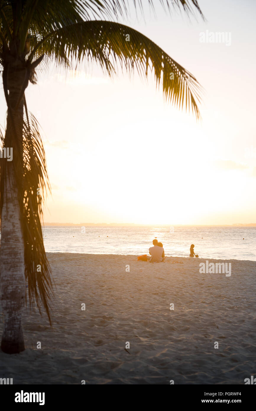 Happy couple in love watching the sunset on a beach on Isla Mujeres, Mexico. Stock Photo
