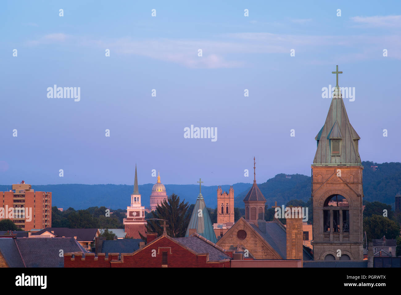 The iconic church steeples line the skyline leading to the capitol building of Charleston, West Virginia against the late evening twilight Stock Photo