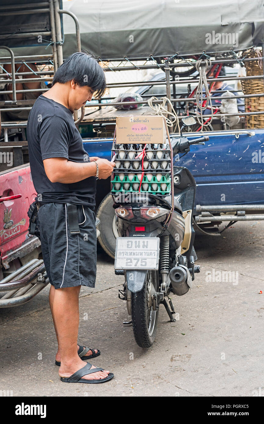 Pak Khlong Talat Market Bangkok - man taking a break having loaded crates of eggs onto his moped Stock Photo