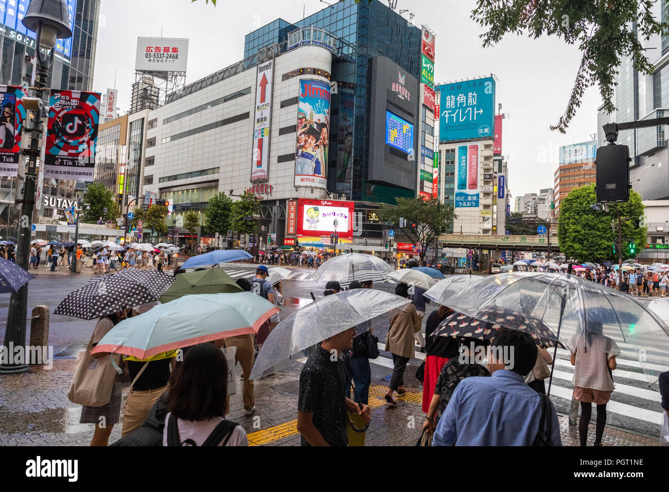 People cross the busy Shibuya intersection in Tokyo on a rainy day ...