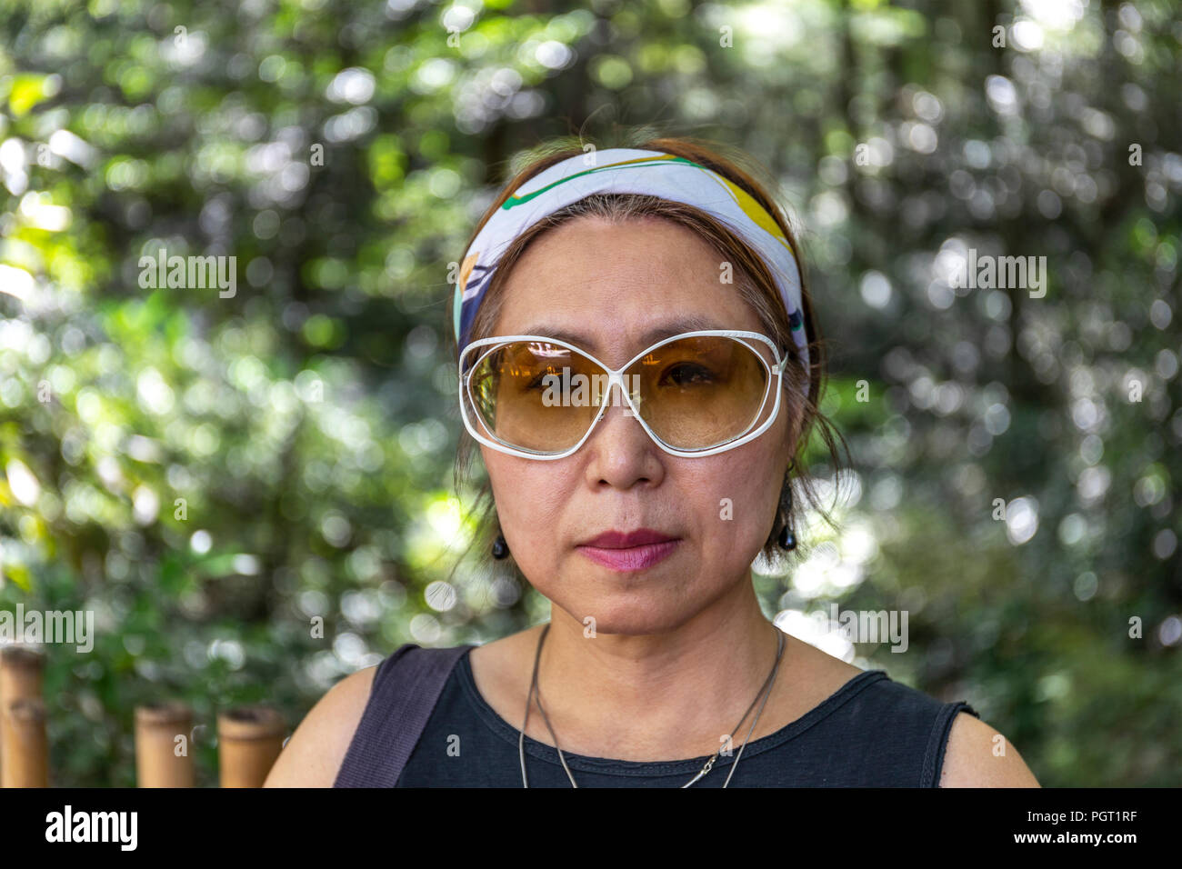 Portrait of confident and self-assured Taiwanese Chinese woman against background of blurred foliage. Stock Photo