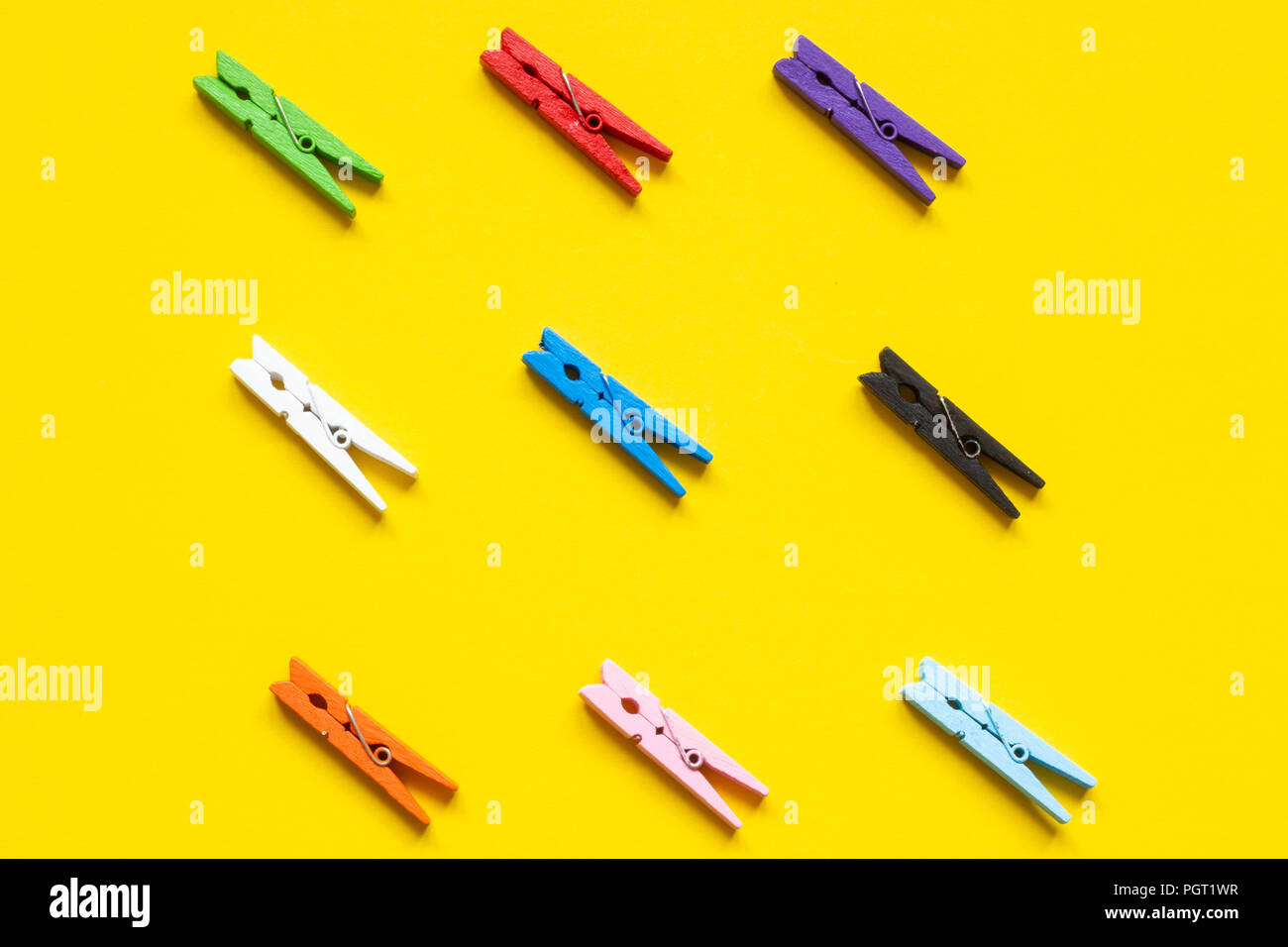 Nine colored clothespins on a yellow background Stock Photo