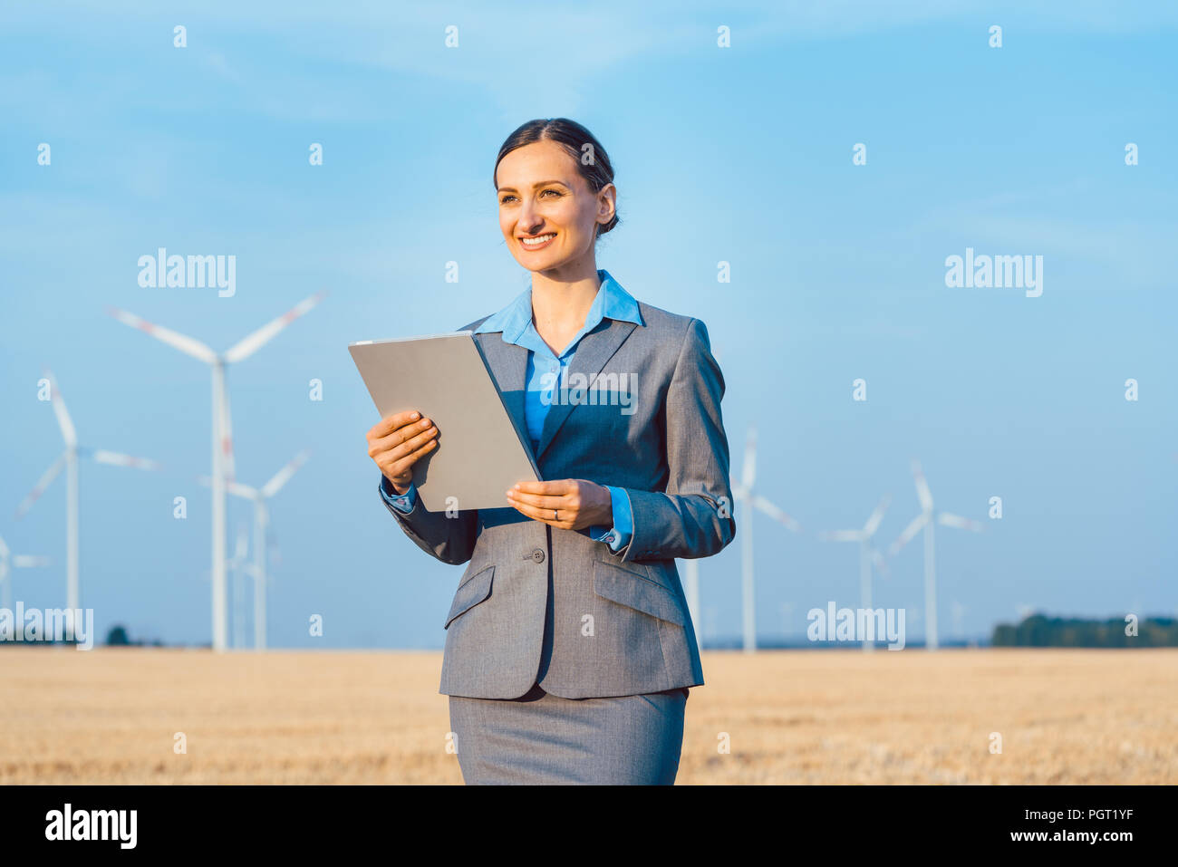 Investor in wind turbines with computer evaluating her investment Stock Photo