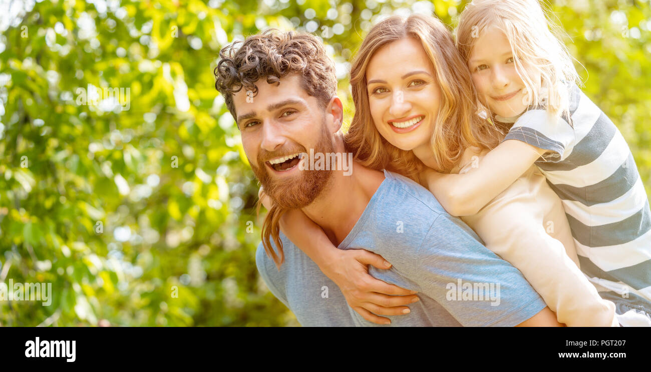 Strong man supporting his family by carrying wife and son Stock Photo