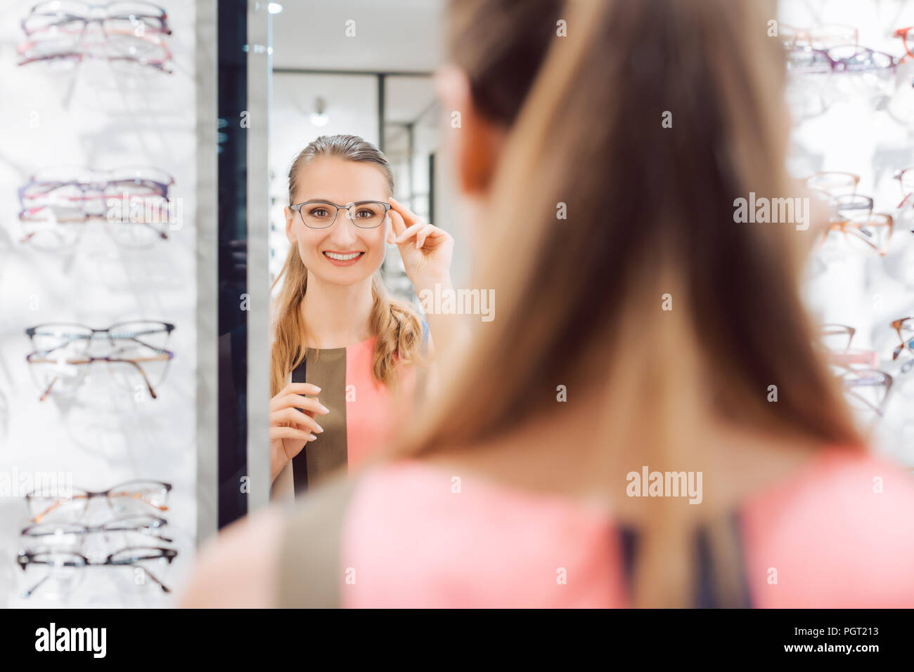 Young woman trying fashionable glasses in optometrist store Stock Photo