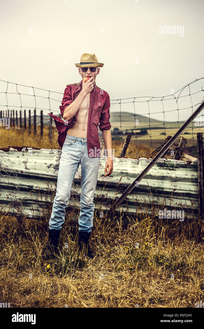 young man wearing straw hat standing in fields Stock Photo
