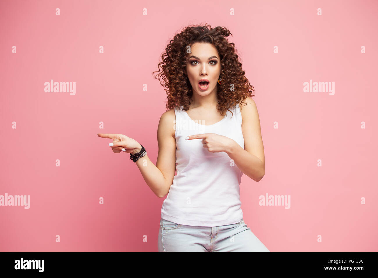Photo of happy young woman standing isolated over pink wall background ...