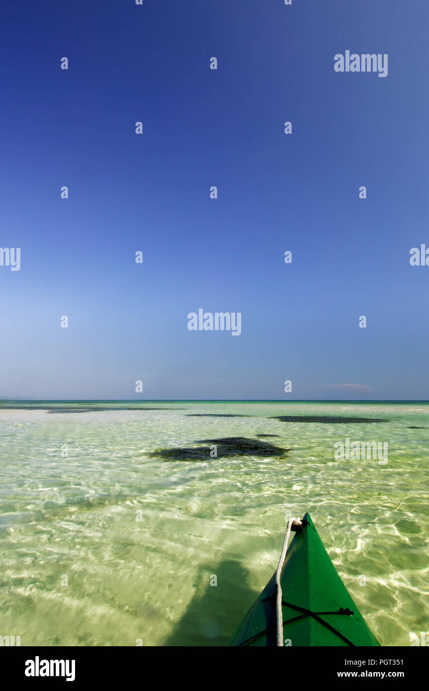 Green kayak floating on clear green water with cobalt blue skies in the