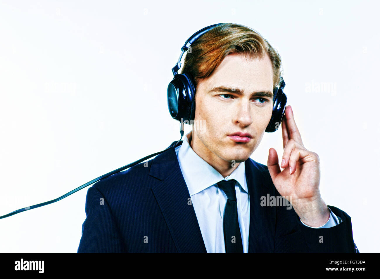Man in suit listening to music on headphones, isolated on white studio