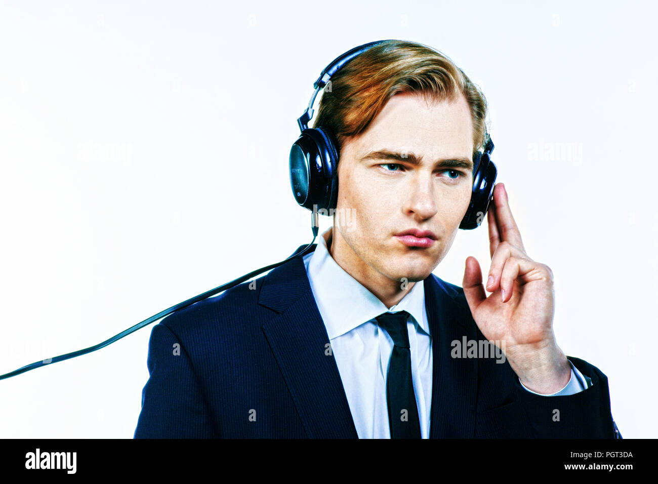 Man in suit listening to music on headphones, isolated on white studio background Stock Photo